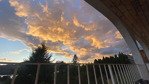 A balcony with a view of a sunset sky and surrounding trees.