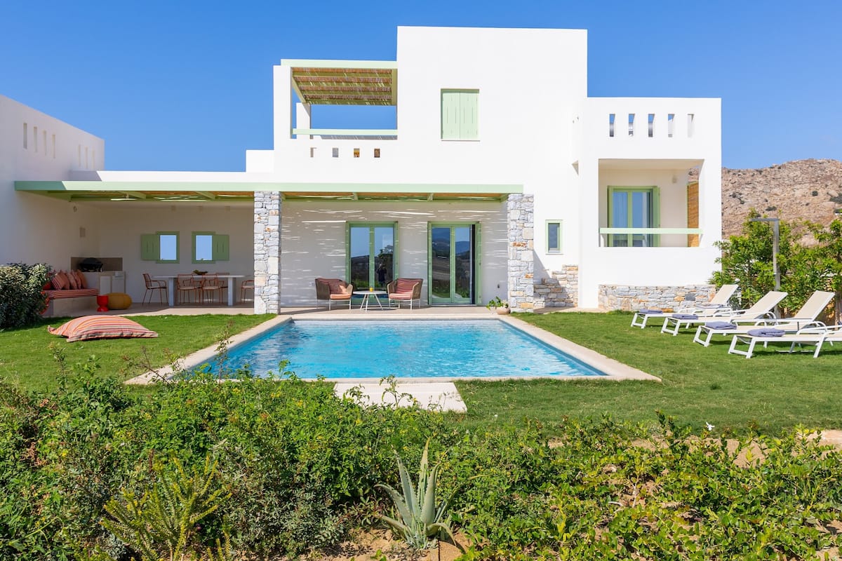 Una casa moderna de dos pisos con piscina, mobiliario exterior y fachada de piedra.