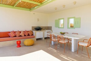 A modern kitchen with a dining area, a sofa with striped cushions, and a yellow ottoman.