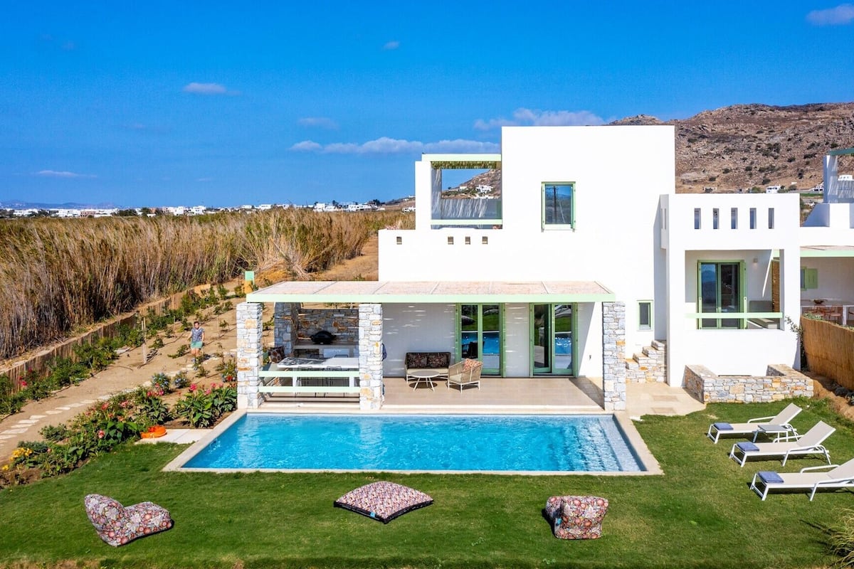 Una casa moderna con piscina, mobiliario exterior y vistas del paisaje circundante.