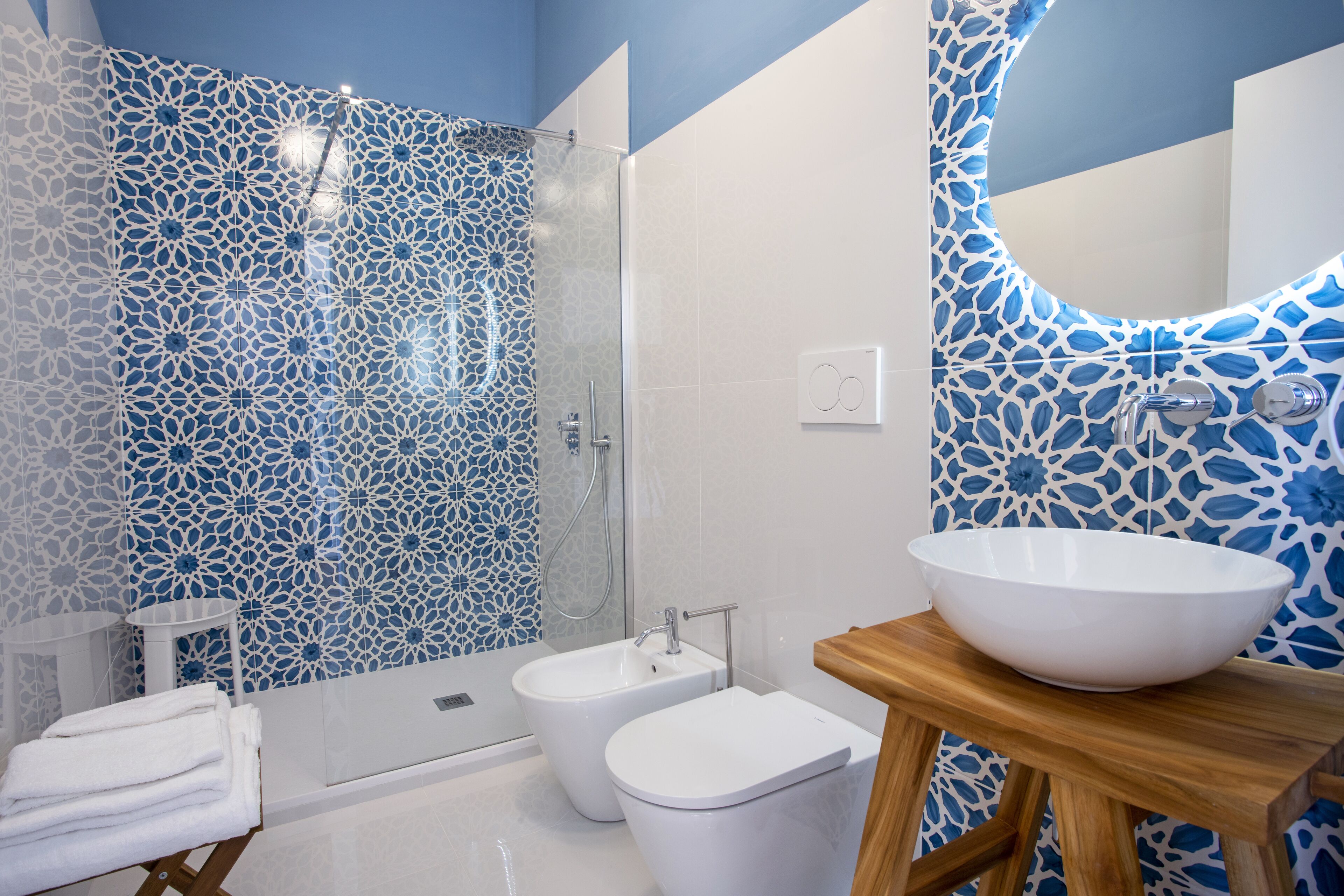 A bathroom with a shower, bidet, and a large sink on a wooden stool.