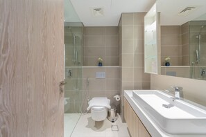 A modern bathroom with a shower, toilet, and a large sink.