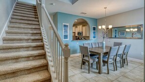 A staircase leading to a dining area with a kitchen in the background.