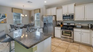 A modern kitchen with white cabinets, stainless steel appliances, and a granite countertop.