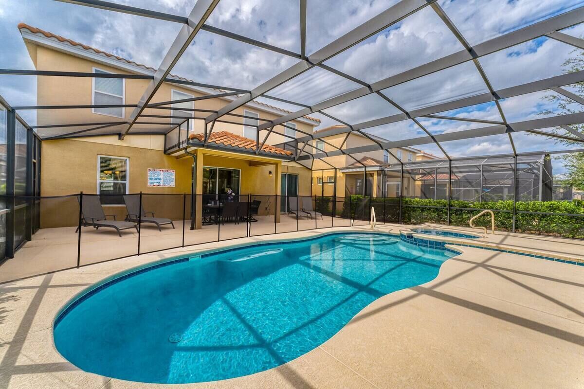 An indoor swimming pool with a glass ceiling, surrounded by lounge chairs and a patio area.