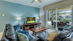 A living room with a TV, two lamps, a coffee table, and leather sofas.