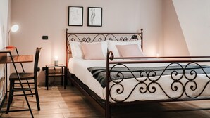Ein Schlafzimmer mit einem Metallbettgestell, einem Holztisch, einem Stuhl und zwei Nachttischen mit Lampen.