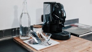 Eine Küchenarbeitsplatte mit einer Kaffeemaschine, einer Glasflasche und einer gerahmten Illustration von Fischen.