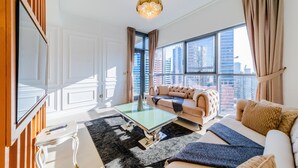 Ein modernes Wohnzimmer mit großem Fenster, einer Couch, einem Couchtisch und einem Fernseher.