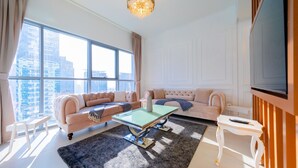 Ein modernes Wohnzimmer mit großem Fenster, einer Sofagarnitur, einem Couchtisch und einem Fernseher.