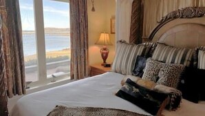 Un dormitorio con una cama grande, vistas al exterior y una lámpara en la mesita de noche.