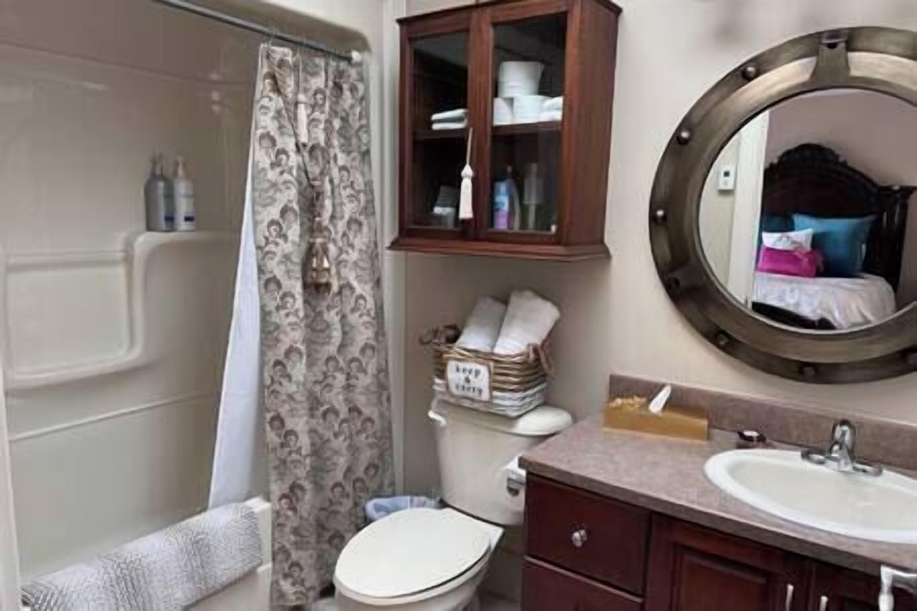 Ein Badezimmer mit Toilette, Waschbecken, Spiegel und Schrank.