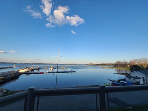 A marina with boats docked, calm water, and a clear sky.