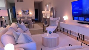 A modern living room with a sofa, armchairs, a coffee table, and a TV. - 3bed -2bath Retreat Sleeps up to 9 w/Amenities+LargerTerrace+Bay Views & Sunset! (Petoskey)