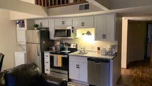 A compact kitchen with white cabinets, a microwave, a refrigerator, and a dishwasher. - Cozy Branson Getaway (Branson)