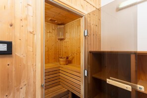 Eine Sauna mit Holzwänden und -bänken, einem Eimer und einer Steuerung.