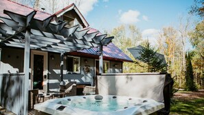 Een jacuzzi voor een huis met een bijzonder dakontwerp en een overdekt terras.
