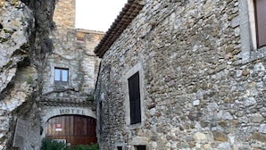 A narrow stone alley with a rustic building featuring a wooden door and a window. - Le Castélas (Aigueze)