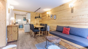 A cozy cabin interior with a dining area, a sofa, and a kitchenette. - Ski-In/Ski-Out | Arc 1800 Center | Steps to ESF & Ski Garden (Bourg-Saint-Maurice)