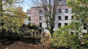 Ein modernes Gebäude mit vielen Fenstern und einer Ziegel-Fassade, umgeben von Bäumen und Grünflächen.