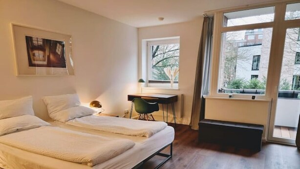 Ein Hotelzimmer mit zwei Betten, einem Schreibtisch und Blick nach außen.