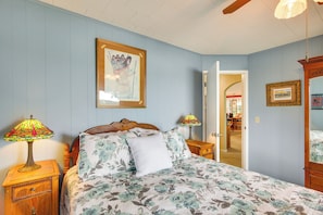 A bedroom with a floral bedspread, two bedside lamps, a wooden headboard, and a framed picture on the wall.