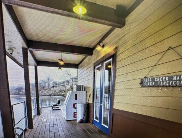 A covered porch with a bench, a trash can, and a sign indicating the location as Fall Creek Main Lake Taneycomo.