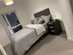 A bedroom with a bed, a nightstand, and a window. - Modern 1-bed Apt, Sleeps 2 in Birmingham (Birmingham)