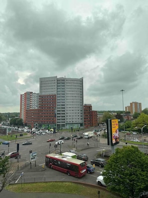 A multi-story building with a modern architectural design, surrounded by a busy urban street with vehicles and a bus. - Modern 1-bed Apt, Sleeps 2 in Birmingham (Birmingham)