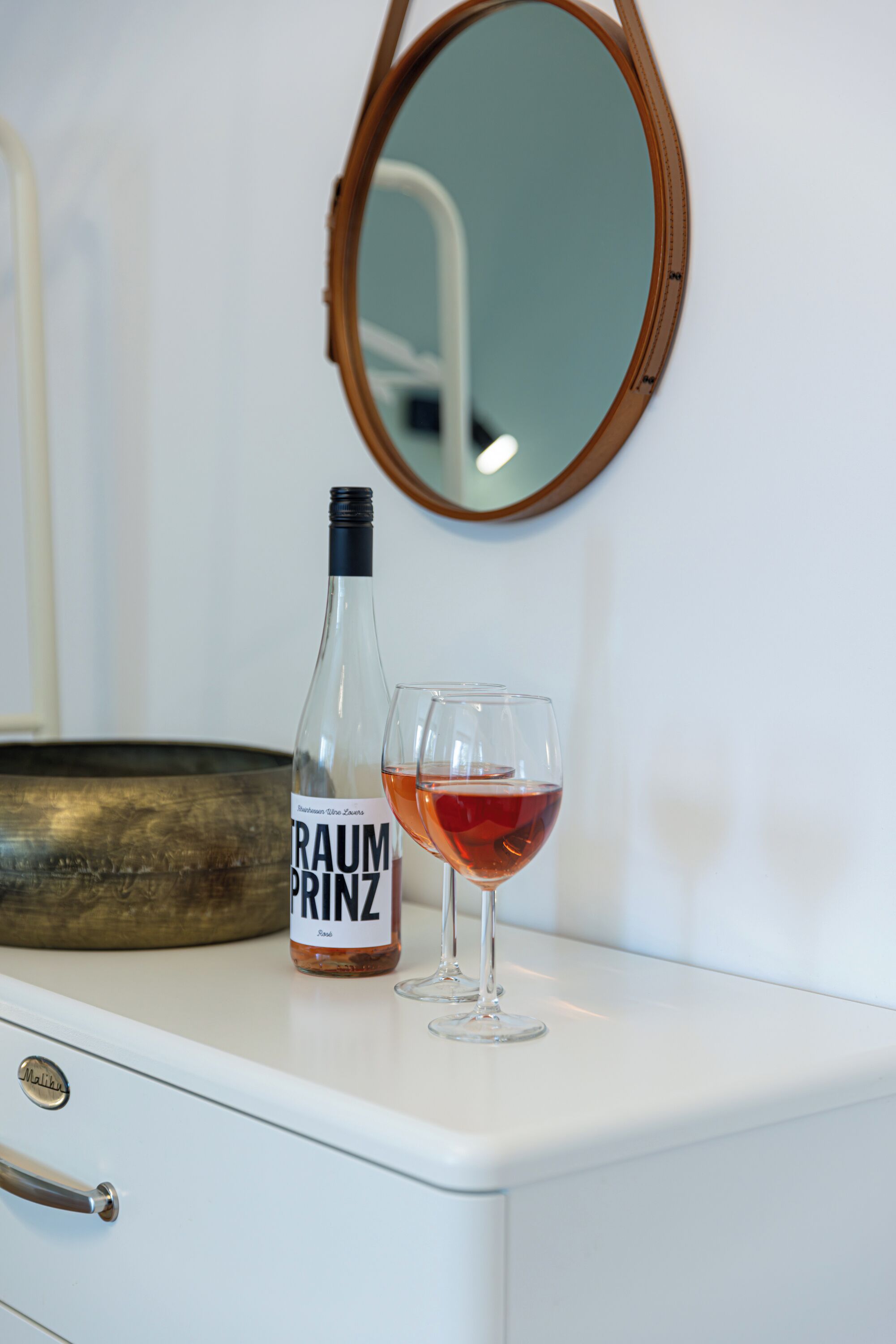 Eine Flasche Traumprinz Wein und ein Glas auf einer weißen Kommode.