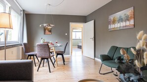 A modern living room with a dining area, wooden flooring, and a view to the kitchen. - Bright & quiet, 200m to the subway (Ahrensburg)