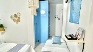 A bedroom with two beds, a blue door, a shelf with books and a picture frame, and wall decorations including circular patterns and soccer balls. - HOTEL KASAYA (Santa Marta)