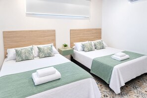 A hotel room with two beds, each with a green bedspread, white pillows, and a small bedside table with a plant. - HOTEL KASAYA (Santa Marta)
