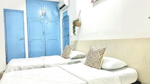 A room with two beds, a blue door, and a wall-mounted air conditioner. - HOTEL KASAYA (Santa Marta)