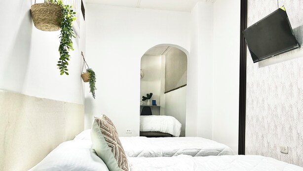 A modern bedroom with a large bed, a hanging plant, and a flat-screen TV mounted on the wall. - HOTEL KASAYA (Santa Marta)