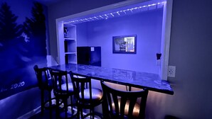 Ein Essbereich mit einem Marmortisch, vier Stühlen, einer integrierten Schrankwand und einem an der Wand befestigten Fernseher.