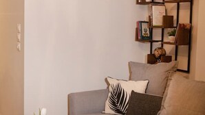 Un salón moderno con un sofá gris, una estantería de madera y un jarrón con flores blancas sobre una mesa de madera.