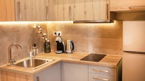 Una cocina moderna con armarios de madera, un lavamanos de acero inoxidable, un hervidor y una estufa empotrada.