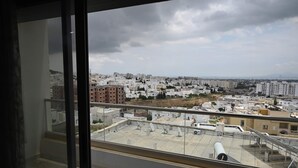 Udsigt over bybilledet fra en balkon med flere bygninger, klar himmel og enkelte skyer.