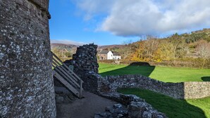 A stone structure with a wooden staircase leading to a white building in a rural setting.