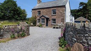 A stone house with a gravel driveway and a stone wall.