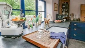 A kitchen with a large window, a scale, a wooden tray, and a sink.