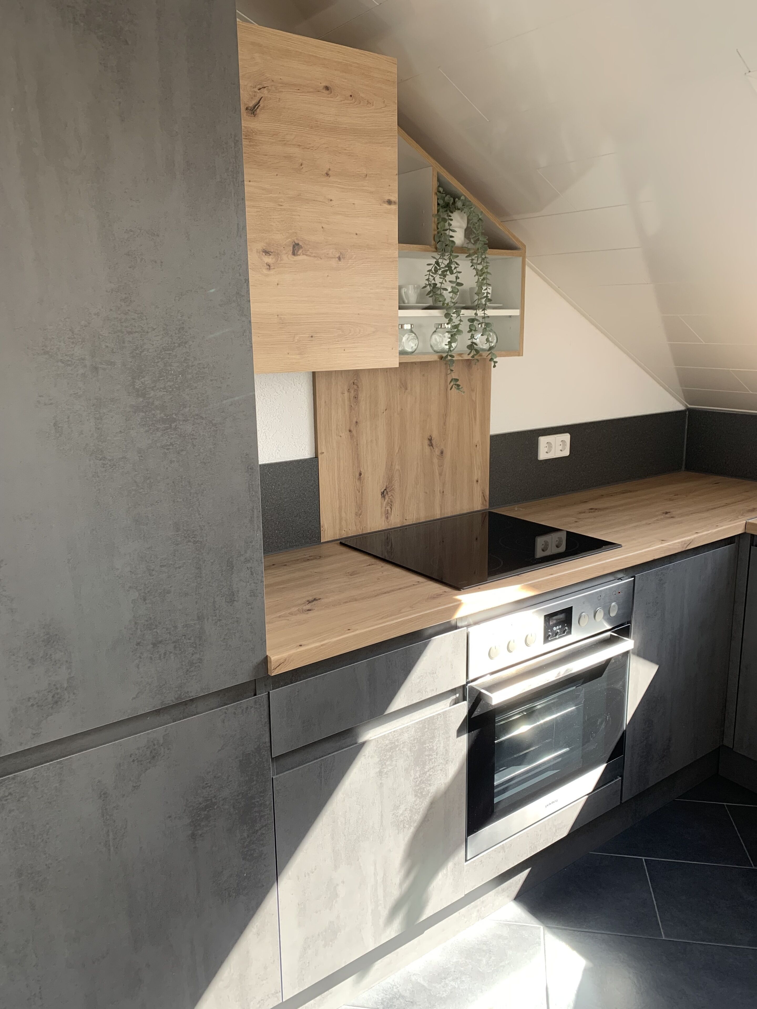 Eine moderne Küche mit Einbauofen, einer Holz Arbeitsplatte und einer hängenden Pflanze.