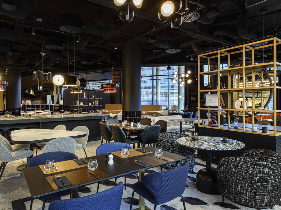 Un intérieur moderne avec des espaces aménagés pour s’asseoir, des tables et un présentoir.