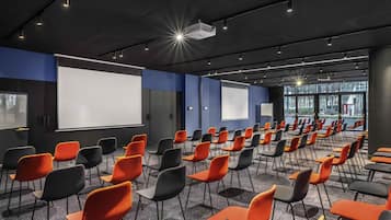 A conference room with rows of chairs, a projector, and a screen.