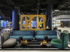 A modern lounge area with a sofa set, side tables, and a decorative partition. - ibis Budapest Stadium  (Budapest)