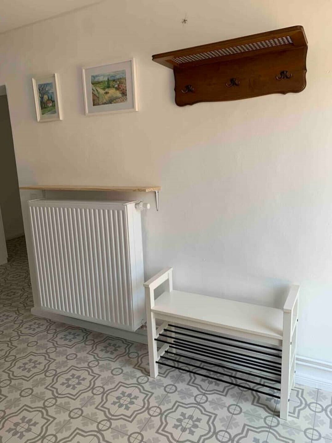 Ein Zimmer mit einem Heizkörper, einer weißen Bank und zwei gerahmten Bildern an der Wand.