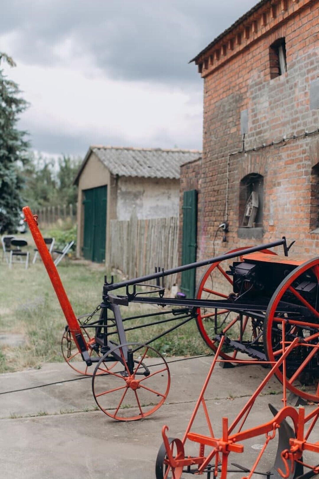 Un vélo rouge et noir, avec de grandes roues rouges, est garé devant un bâtiment en briques dont la porte est verte.