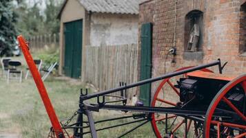 Un vélo rouge et noir, avec de grandes roues rouges, est garé devant un bâtiment en briques dont la porte est verte.