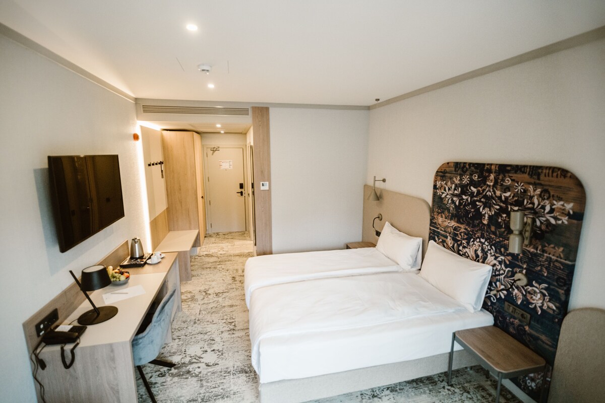 Une chambre d’hôtel équipée d’un lit, d’une table de chevet, d’une lampe et d’un téléviseur fixé au mur.